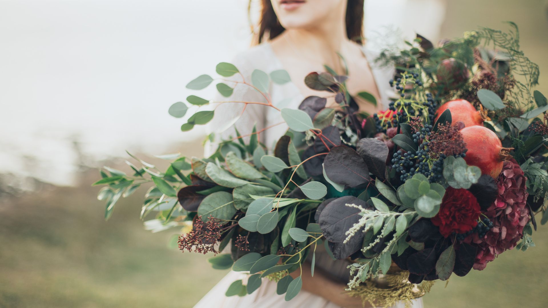 Junge Frau mit einem bunten Pflanzen- und Blumenstrauß